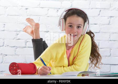 Jeune fille avec casque à faire des devoirs sur marbre Banque D'Images