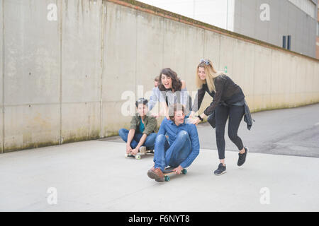 Groupe de jeunes amis multiethnique s'amusant, riant et souriant, assis sur leurs courses skateboard - amitié, fun concept Banque D'Images