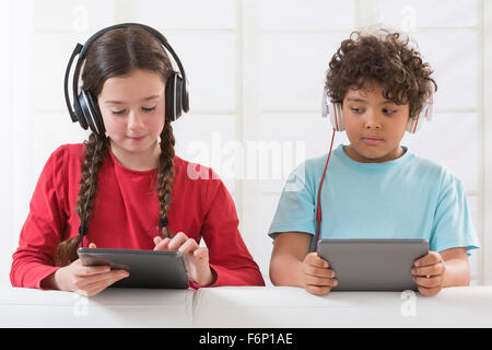 Frères et sœurs à l'aide de tablette numérique tout en écoutant de la musique Banque D'Images