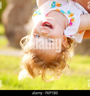 Heureux bébé jouant et riant à l'envers. Banque D'Images