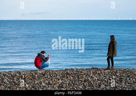 Un homme de prendre une photo d'une femme sur la plage de Llandudno, Conwy, Pays de Galles, Royaume-Uni Banque D'Images