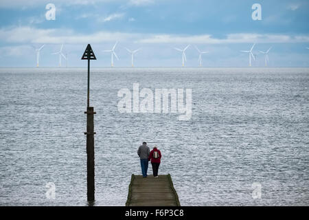 Une femme et un homme âgés se tiennent sur une jetée de Llandudno, au Pays de Galles, en face de Gwynt y Mor parc éolien offshore en mer d'Irlande. Banque D'Images