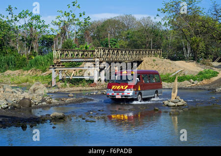 Traversée par la rivière Taxi rouler dans l'eau à côté du pont inachevé au Costa Rica Banque D'Images