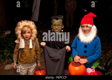 Trois enfants vêtus de leurs costumes de Halloween trick ou traiter. St Paul Minnesota MN USA Banque D'Images