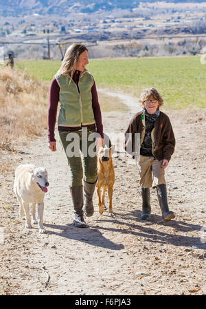 Belle Mère, jeune fils et des chiens de marcher le long chemin de terre sur ranch Banque D'Images