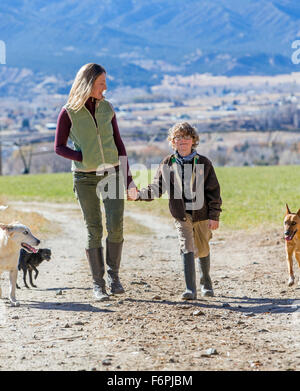 Belle Mère, jeune fils et des chiens de marcher le long chemin de terre sur ranch Banque D'Images