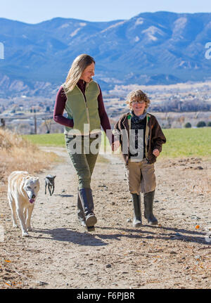 Belle Mère, jeune fils et des chiens de marcher le long chemin de terre sur ranch Banque D'Images