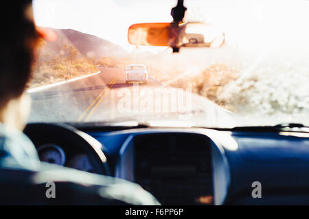 Caucasian man driving car sur route à distance Banque D'Images