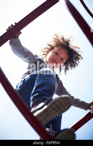 Low angle view of mixed race boy escalade sur structure de jeux Banque D'Images