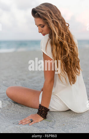 Hispanic woman sitting on beach Banque D'Images