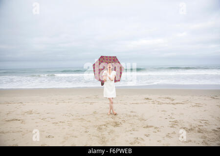 Woman Laughing with umbrella on beach Banque D'Images