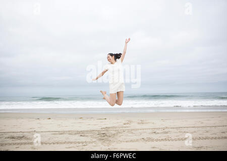 Femme sautant de joie sur la plage Banque D'Images