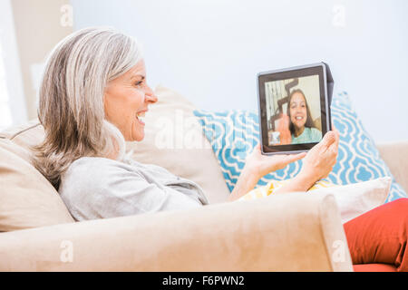 Grand-mère de race blanche avec petite-fille videochatting on digital tablet Banque D'Images