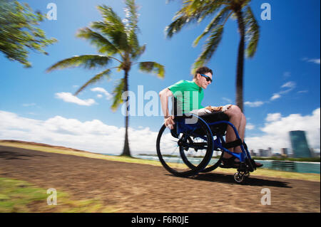 Homme handicapé en fauteuil roulant de course par urban beach Banque D'Images