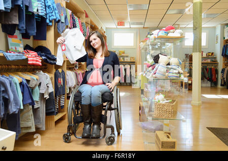 Femmes enceintes paraplegic woman in wheelchair shopping en magasin bébé Banque D'Images