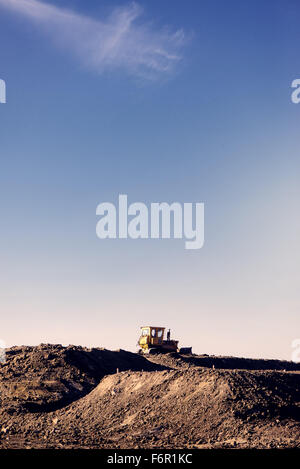 Pelle chargeuse à eathmoving travaille en construction site, retro tachée copy space Banque D'Images