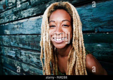 Black woman smiling at wooden wall Banque D'Images