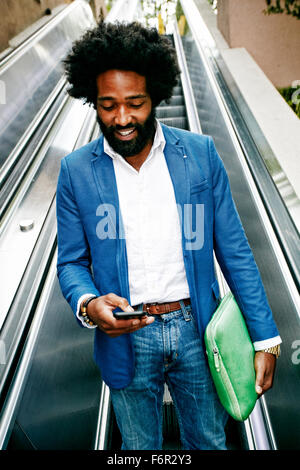 Mixed Race businessman using cell phone on escalator Banque D'Images