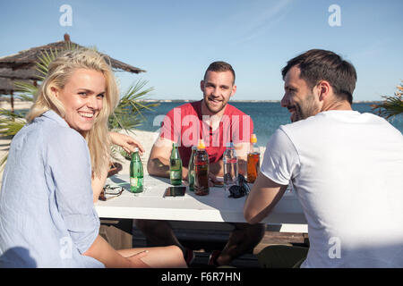 Groupe d'amis célébrant dans bar de plage Banque D'Images