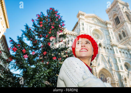 Happy young woman in white sweater debout devant l'arbre de Noël traditionnel près du Dôme de Florence, en Italie. Elle a inspiré b Banque D'Images
