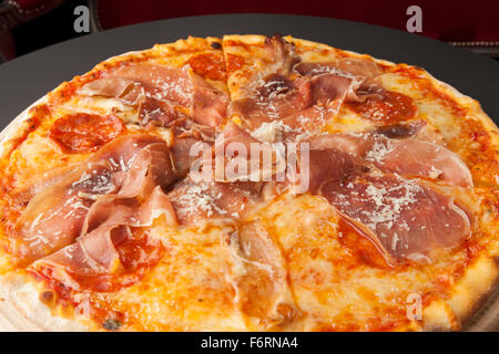 Pizza au jambon et saucisse sur plaque de bois Banque D'Images