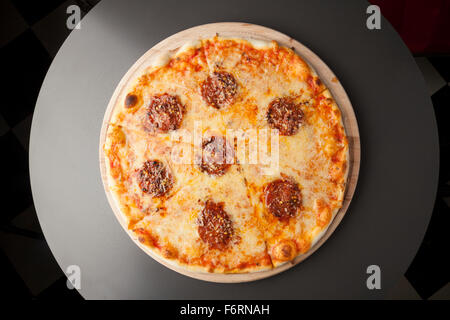 Pizza au pepperoni, avec de la saucisse sur plaque de bois Banque D'Images