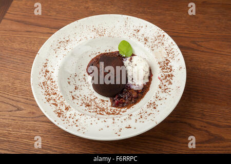 Gâteau au chocolat avec de la crème glacée aux fruits rouges, et le sommet, servi dans une assiette blanche Banque D'Images