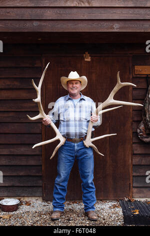 Caucasian farmer holding antlers on Front Porch Banque D'Images