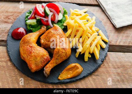 Cuisses de poulet rôti avec frites et salade Banque D'Images