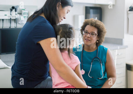 Doctor talking to mother and daughter in hotel room Banque D'Images