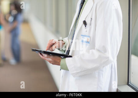 Doctor using digital tablet in hallway Banque D'Images