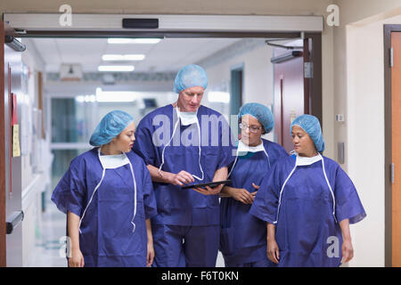 Surgeons using digital tablet in hospital hallway Banque D'Images