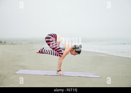 Caucasian woman practicing yoga on beach Banque D'Images