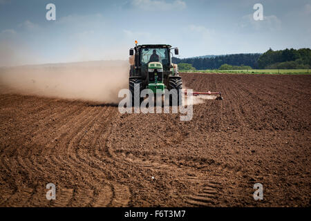 La poussière qu'il crée du tracteur remorque une grand semoir derrière elle tandis que les semis de graines. Banque D'Images
