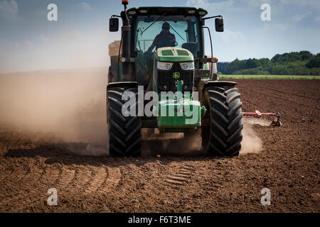 La poussière qu'il crée du tracteur remorque une grand semoir derrière elle. Banque D'Images