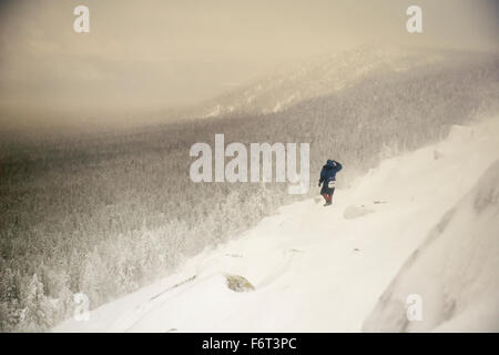 Caucasian hiker se réveiller sur snowy hillside Banque D'Images