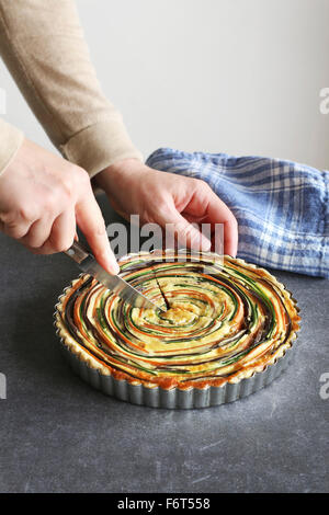Les mains de trancher une tarte aux légumes Banque D'Images