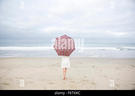 Femme debout avec umbrella on beach Banque D'Images