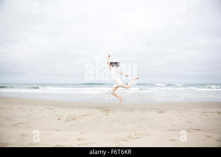 Femme sautant de joie sur la plage Banque D'Images