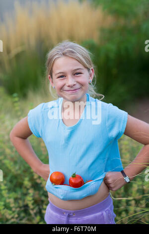 Caucasian girl transportant des tomates dans shirt Banque D'Images