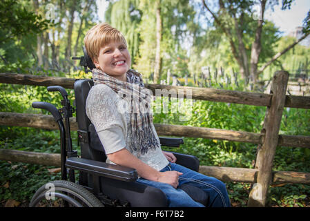 Paraplegic woman in wheelchair smiling in garden Banque D'Images