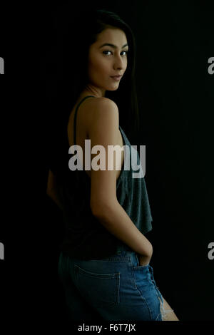 Hispanic woman looking over shoulder Banque D'Images