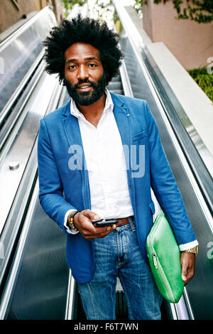 Mixed Race businessman using cell phone on escalator Banque D'Images