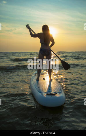 Femme debout sur le lac en paddleboard Banque D'Images