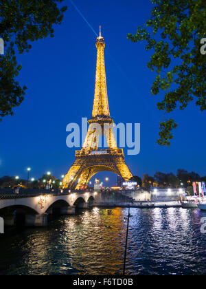 La Tour Eiffel éclairée au crépuscule et se reflétant dans la Seine. Un projecteur éclaire par le haut. Paris, Île-de-France, France Banque D'Images