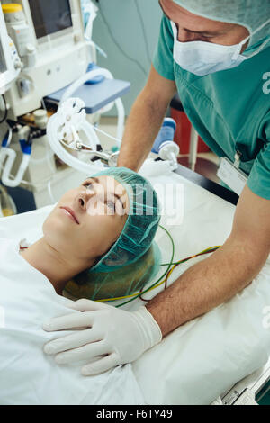 Infirmière d'exploitation soothing patient sur table en salle d'opération Banque D'Images