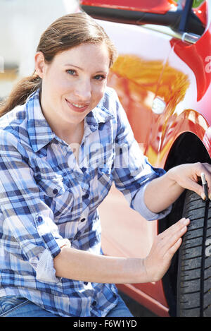 Femme Contrôle de la voie sur pneu de voiture avec manomètre Banque D'Images