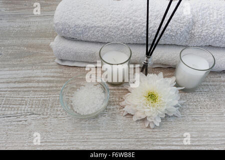 Composition Spa avec les serviettes blanches, des bougies, des fleurs, d'encens et sels de bain sur table en bois Banque D'Images