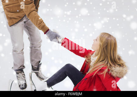 L'homme aide les femmes à se soulever sur patinoire Banque D'Images