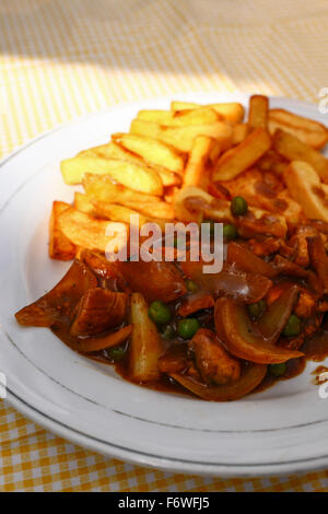 Sauté de poulet au curry et frites sur une nappe jaune vérifié Banque D'Images